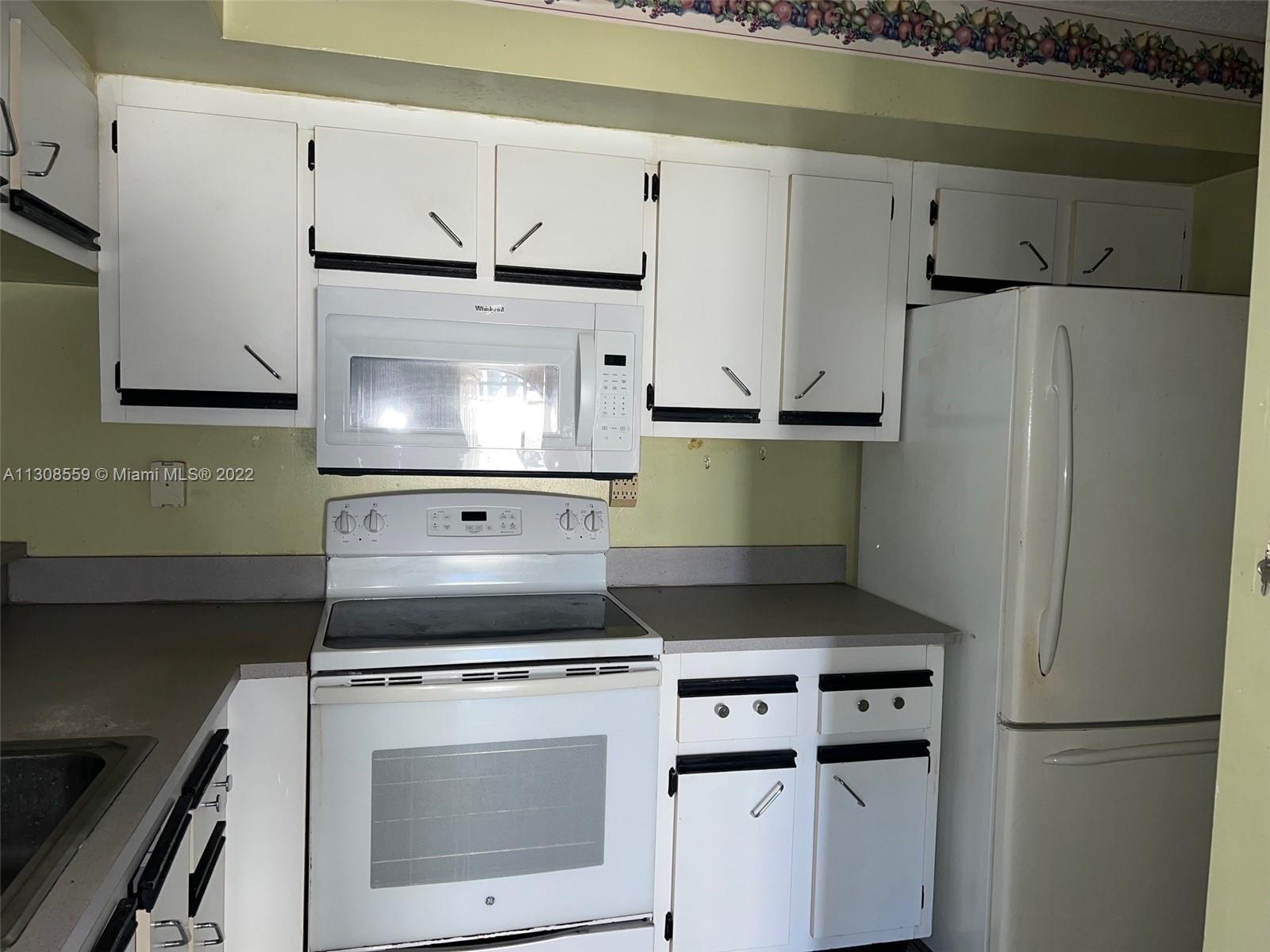 18230 Mediterranean Boulevard, Unit 113 Hialeah, FL 33015 - Photo 7 of 18 a kitchen with granite countertop a refrigerator and a stove