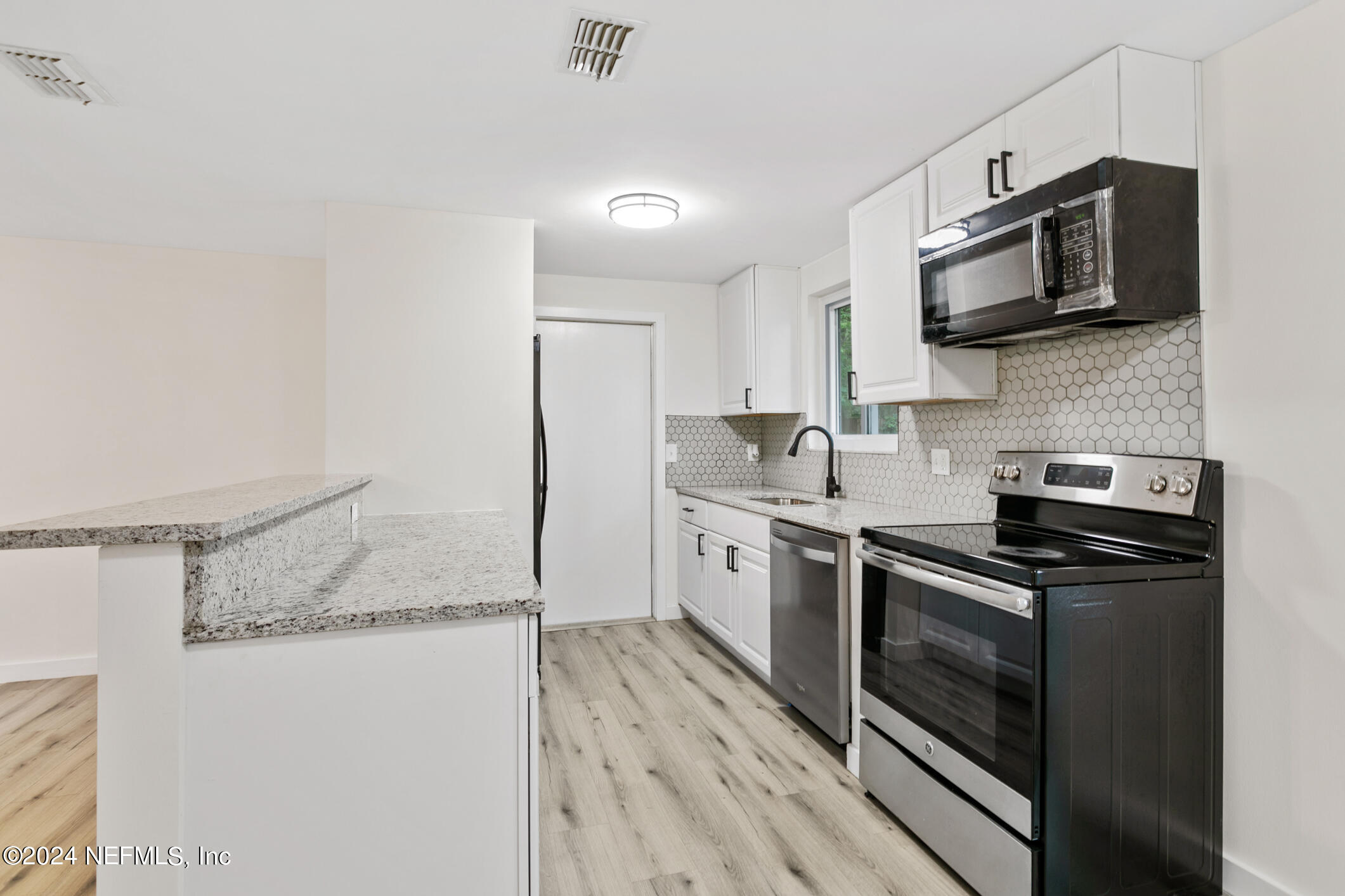 4216 Oriely Drive Jacksonville, FL 32210 - Photo 16 of 36 a kitchen with stainless steel appliances granite countertop a stove top oven a sink and a microwave