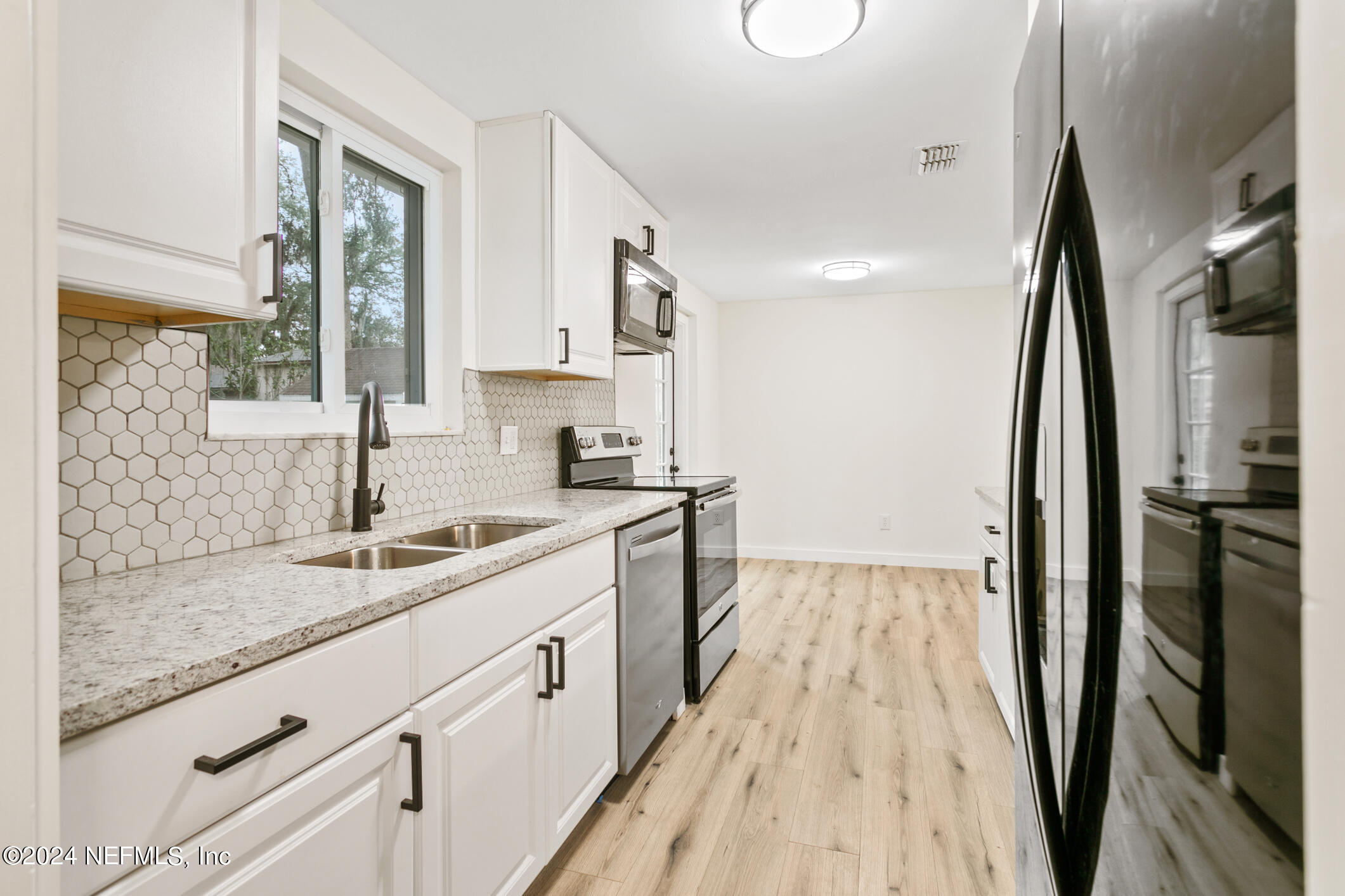 4216 Oriely Drive Jacksonville, FL 32210 - Photo 5 of 36 a kitchen with a sink a refrigerator a window and cabinets