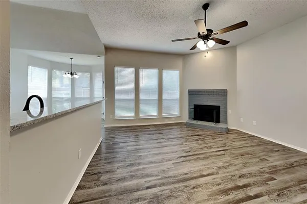 a view of an empty room with chandelier fan and wooden floor