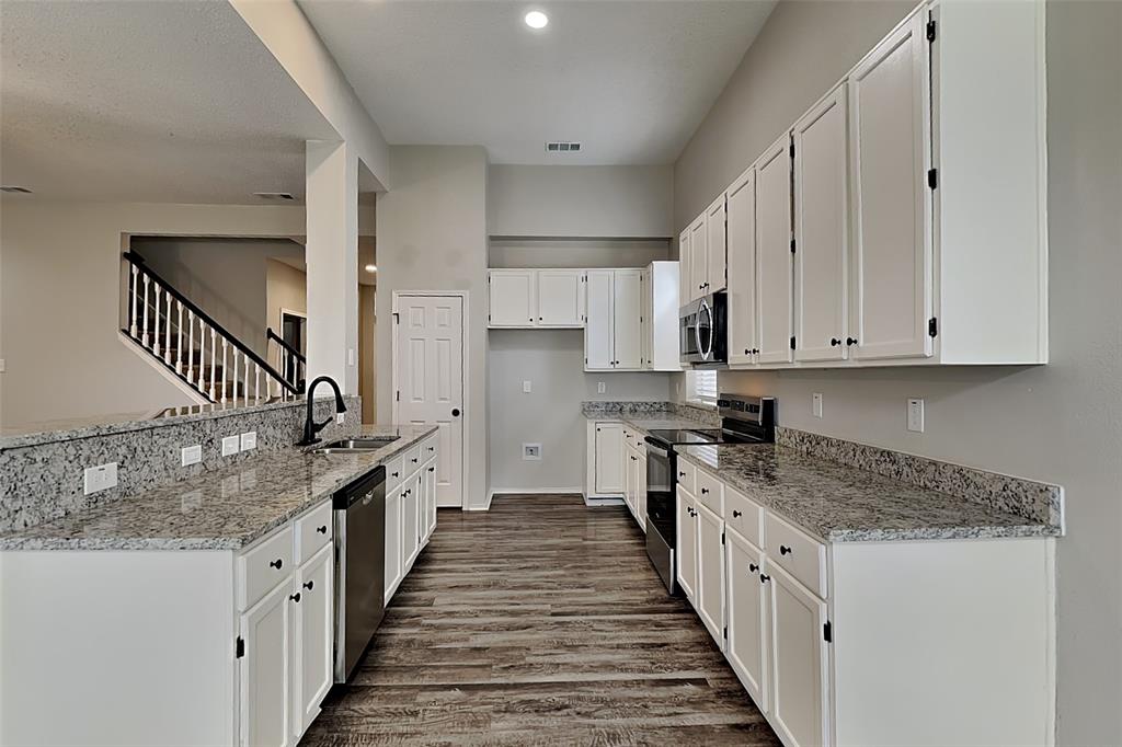2224 Red Maple Road Flower Mound, TX 75022 - Photo 4 of 22 a kitchen with granite countertop a sink and dishwasher a stove top oven with wooden floor