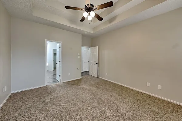 an empty room with chandelier fan and windows