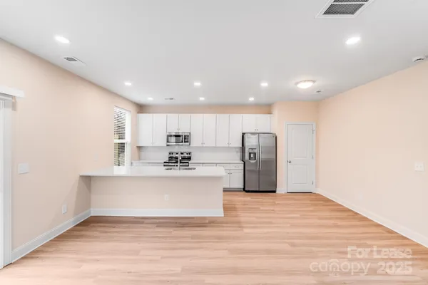 a view of kitchen with stainless steel appliances wooden floor and window