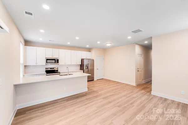 a kitchen with counter top space a sink wooden floor and stainless steel appliances