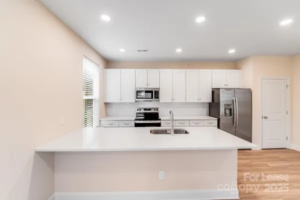 a kitchen with a refrigerator a stove top oven a sink and cabinets