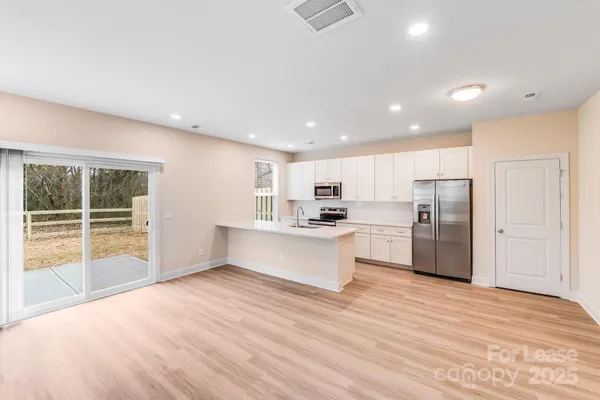 a large kitchen with a center island wooden floor stainless steel appliances and windows