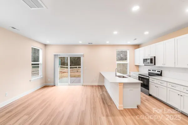 a view of kitchen with stainless steel appliances refrigerator stove microwave and cabinets