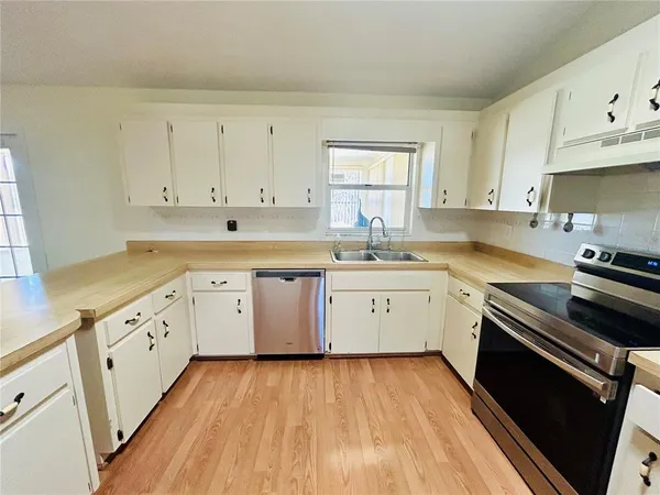 a kitchen with wooden floors appliances cabinets and a sink