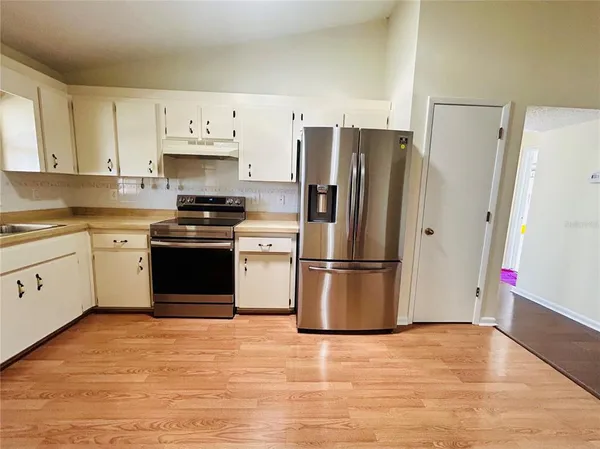 a kitchen with stainless steel appliances a refrigerator stove and white cabinets