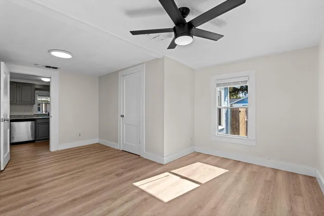 an empty room with wooden floor cabinet and windows