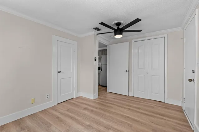 a view of empty room with wooden floor and ceiling fan