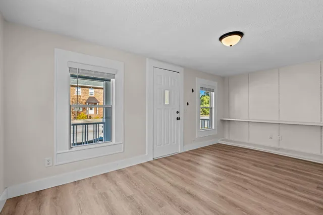 a view of an empty room with window and wooden floor