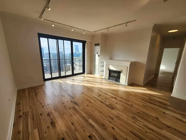 a view of empty room with wooden floor and fireplace