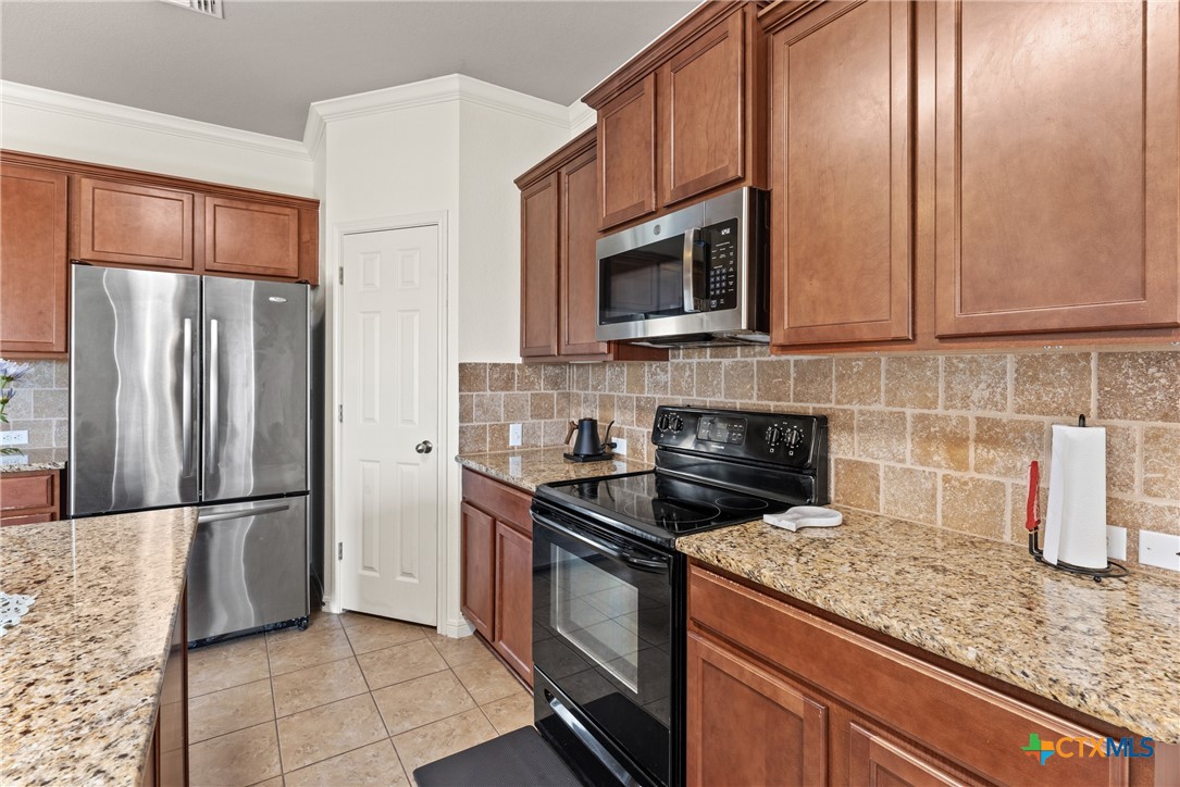 305 Brunswick Temple, TX 76502 - Photo 26 of 28 a kitchen with granite countertop a refrigerator stove and microwave
