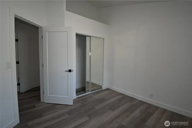 a view of an empty room with wooden floor and closet