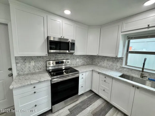 a kitchen with white cabinets appliances and a sink