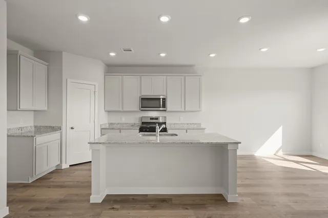 a large white kitchen with kitchen island a sink a stove a refrigerator and white cabinets