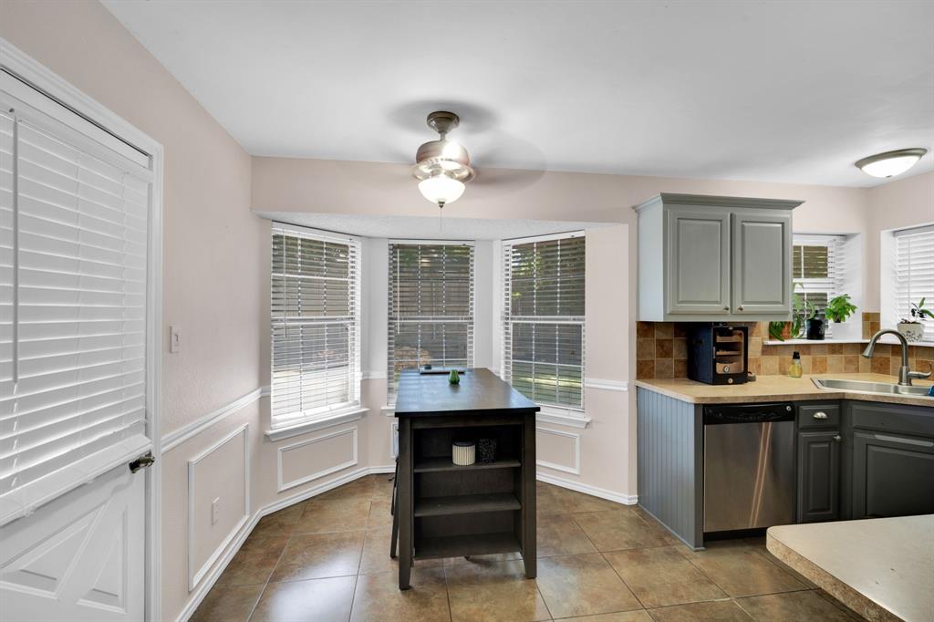 1001 Short Line Boulevard Midlothian, TX 76065 - Photo 19 of 26 Kitchen area featuring a bay window, tile flooring, grey cabinetry, stainless steel dishwasher, and a ceiling fan with integrated lighting