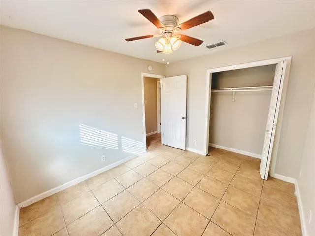 a view of an empty room and window with a chandelier fan
