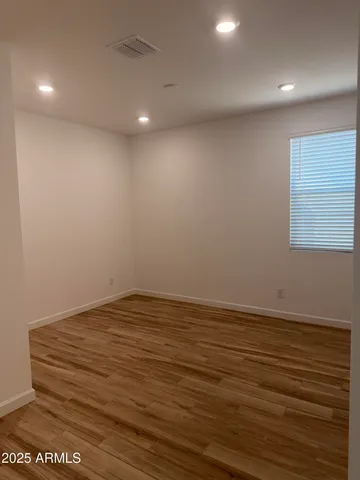an empty room with wooden floor and fan