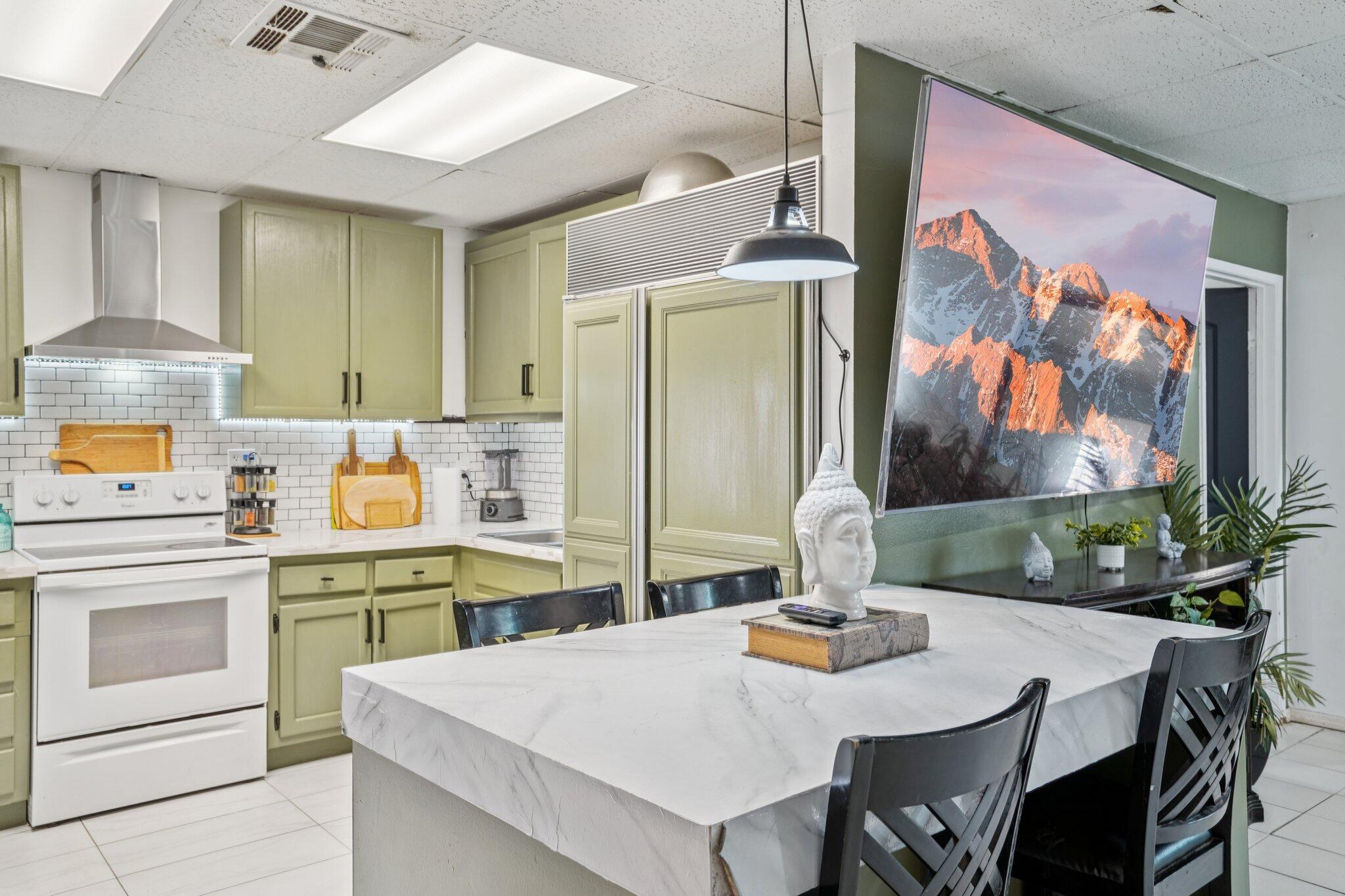 2154 Riviera Circle Thermal, CA 92274 - Photo 12 of 43 a kitchen with stainless steel appliances a white stove top oven a dining table and chairs with wooden floor