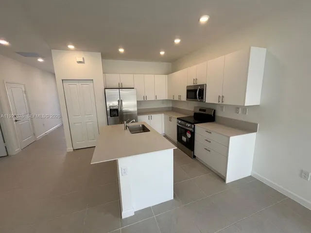 a kitchen with stainless steel appliances kitchen island sink refrigerator and stove