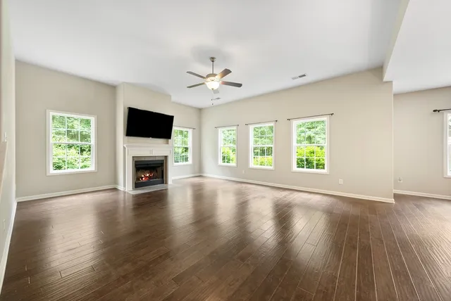 a view of an empty room with wooden floor and a fireplace