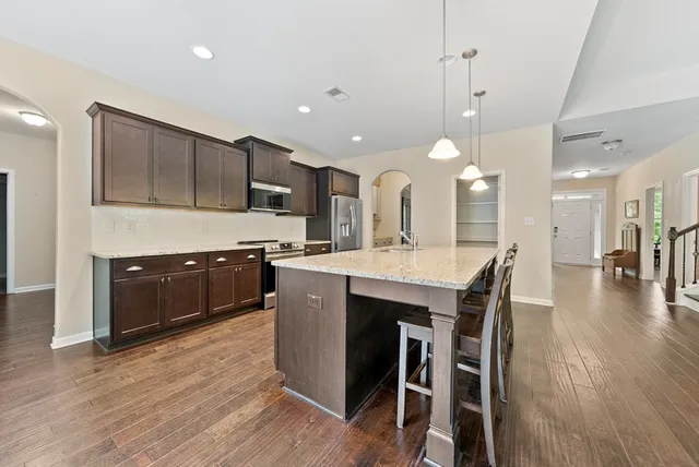 a kitchen with stainless steel appliances kitchen island granite countertop wooden floors and view of living room