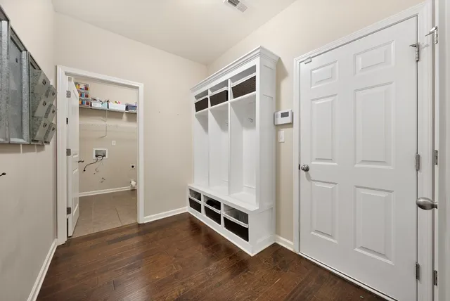 a view of an empty room with wooden floor and a bathroom