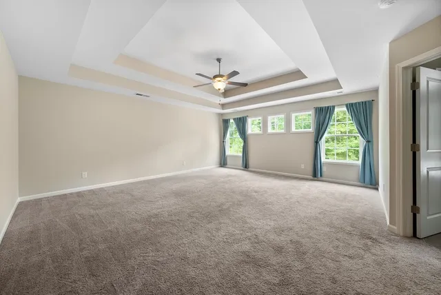 an empty room with windows and ceiling fan