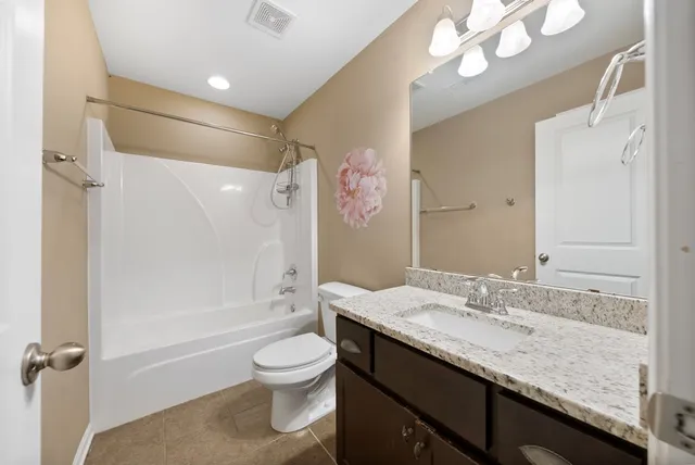 a bathroom with a granite countertop sink a toilet a mirror a vanity and shower