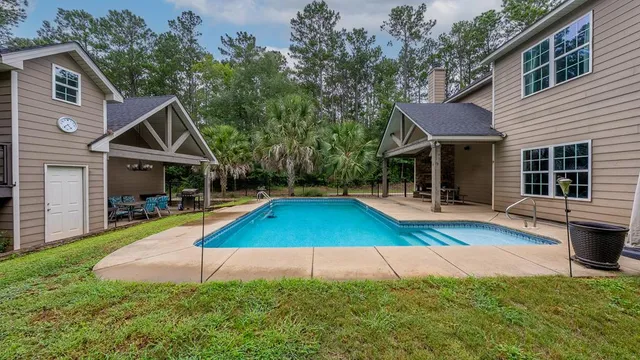 a view of house with swimming pool outdoor seating and barbeque oven