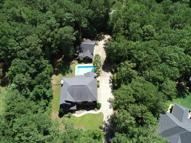 an aerial view of a house with yard outdoor and trees all around