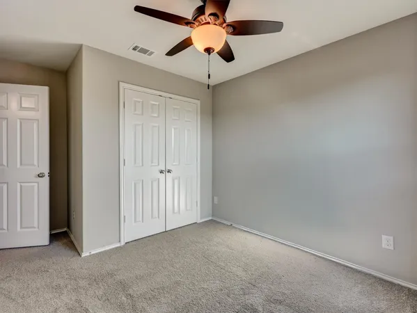 an empty room with a chandelier fan and a ceiling fan
