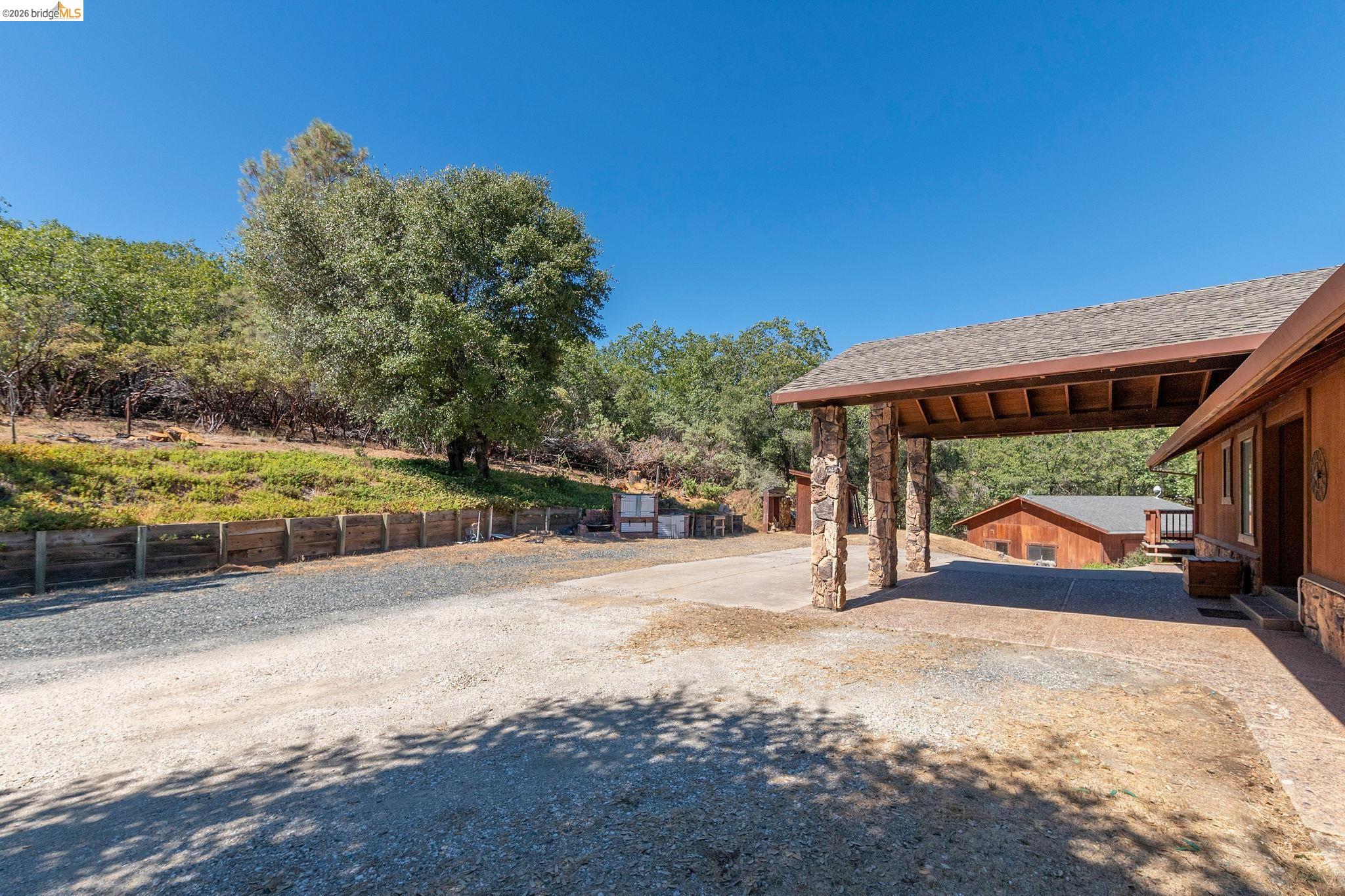 22963 Robertson Ranch Road Sonora, CA 95370 - Photo 66 of 90 Covered carport with stone-clad columns and a shingle roof