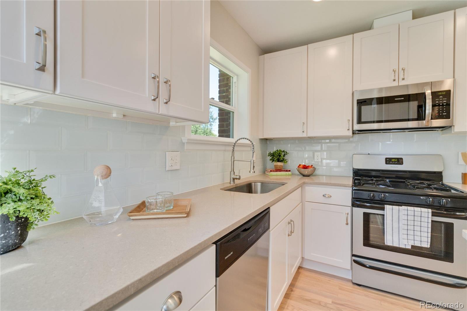 1325 Dahlia Street Denver, CO 80220 - Photo 16 of 44 a kitchen with stainless steel appliances white cabinets and a stove top oven