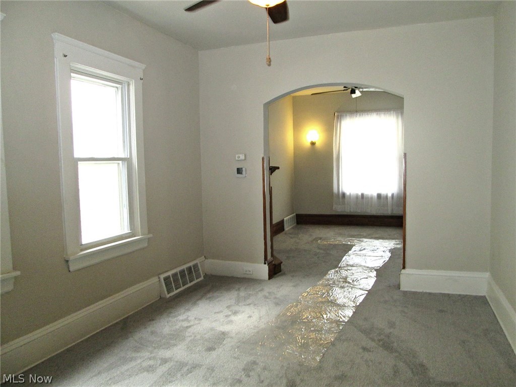 The dining room looking into the living room (fp mantle visible in archway). Newly carpeted and neutral colors.