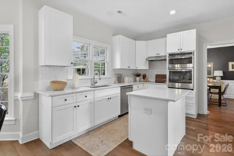 a kitchen with granite countertop a sink cabinets stainless steel appliances and a window