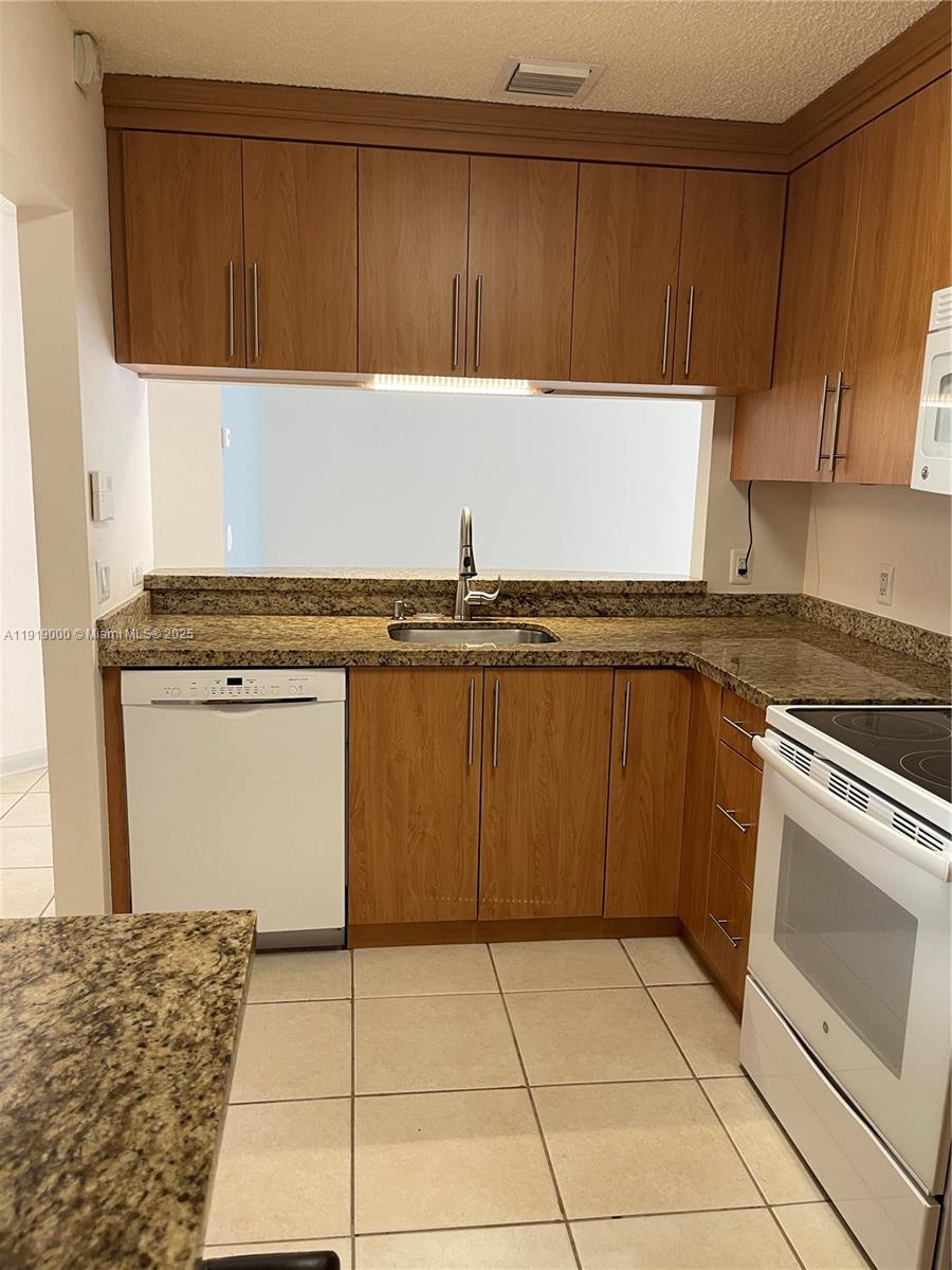 11740 Southwest 19th Street, Unit 11740 Miramar, FL 33025 - Photo 19 of 29 a kitchen with a cabinets a sink and a stove top oven