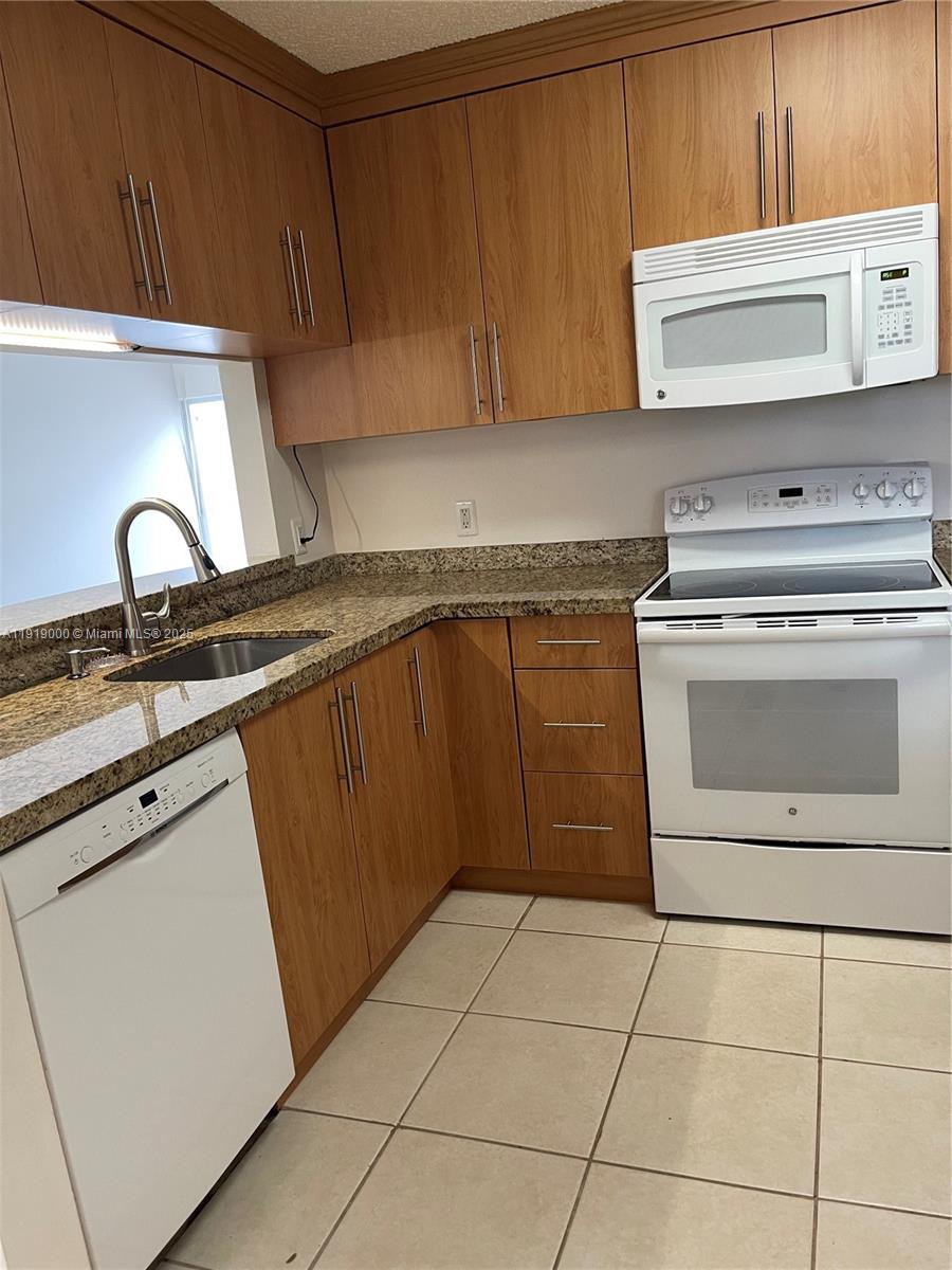 11740 Southwest 19th Street, Unit 11740 Miramar, FL 33025 - Photo 20 of 29 a kitchen with granite countertop a stove a sink and a microwave