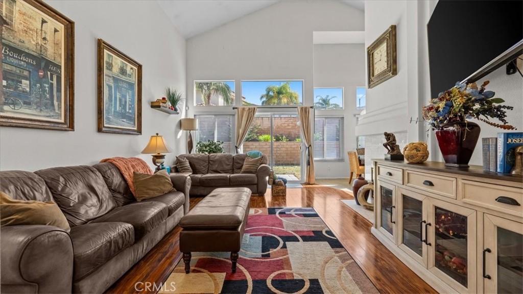 1671 Dominguez Ranch Road Corona, CA 92878 - Photo 5 of 42 This inviting living room showcases vaulted ceilings, rich wood flooring, and abundant natural light from large windows and sliding glass doors. A cozy fireplace and open layout make it ideal for everyday living and entertaining.