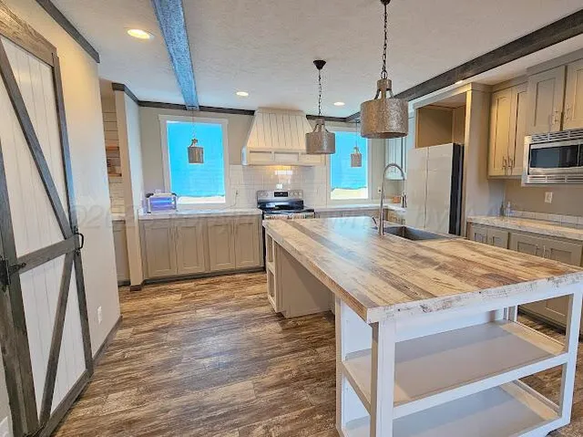 a kitchen with stainless steel appliances granite countertop a kitchen island hardwood floor and a sink