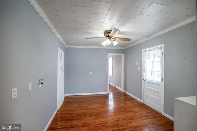 a view of an empty room with a chandelier fan and wooden floor