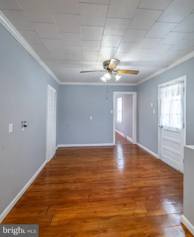 a view of an empty room with window and wooden floor