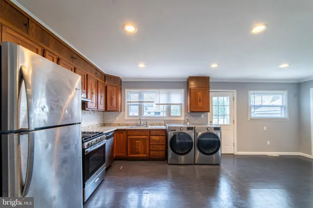 a kitchen with stainless steel appliances granite countertop a refrigerator a sink a stove and a wooden floors