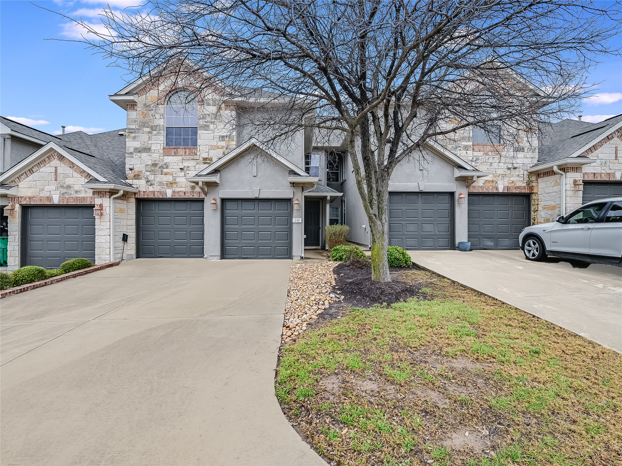 230 Sunrise Ridge Loop Austin, TX 78738 - Photo 2 of 27 Stone and stucco accents highlight this attractive townhome with individual garage access.