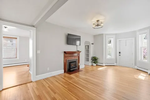 a view of a livingroom with a fireplace a chandelier and wooden floor