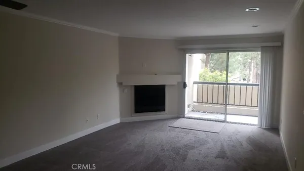 an empty room with floor to ceiling window and an outdoor view