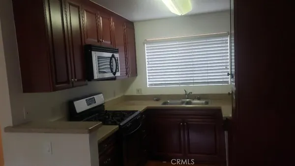 a kitchen with granite countertop stainless steel appliances a sink stove and cabinets