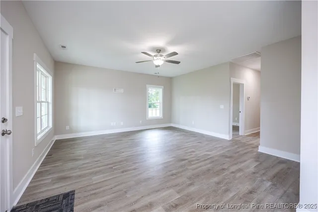 a view of an empty room with a window and wooden floor